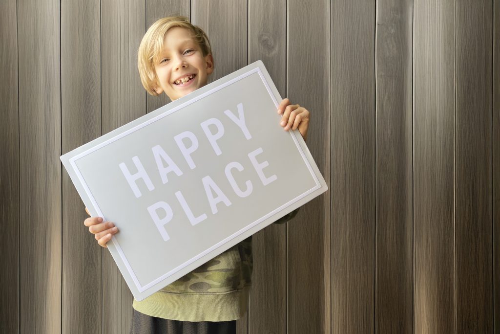 Boy holding a sign the says happy place.