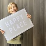 Boy holding a sign the says happy place.